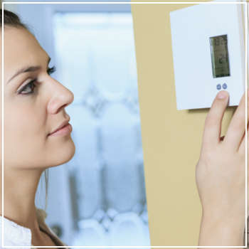 woman adjusting her thermostat