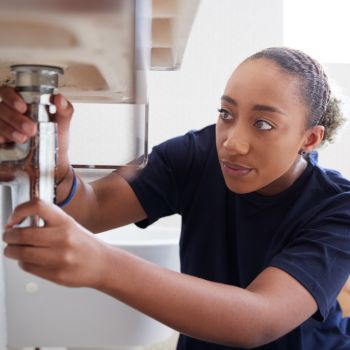 woman fixing sink leak in bathroom